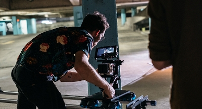 A camera operator uses video equipment on a parking garage.