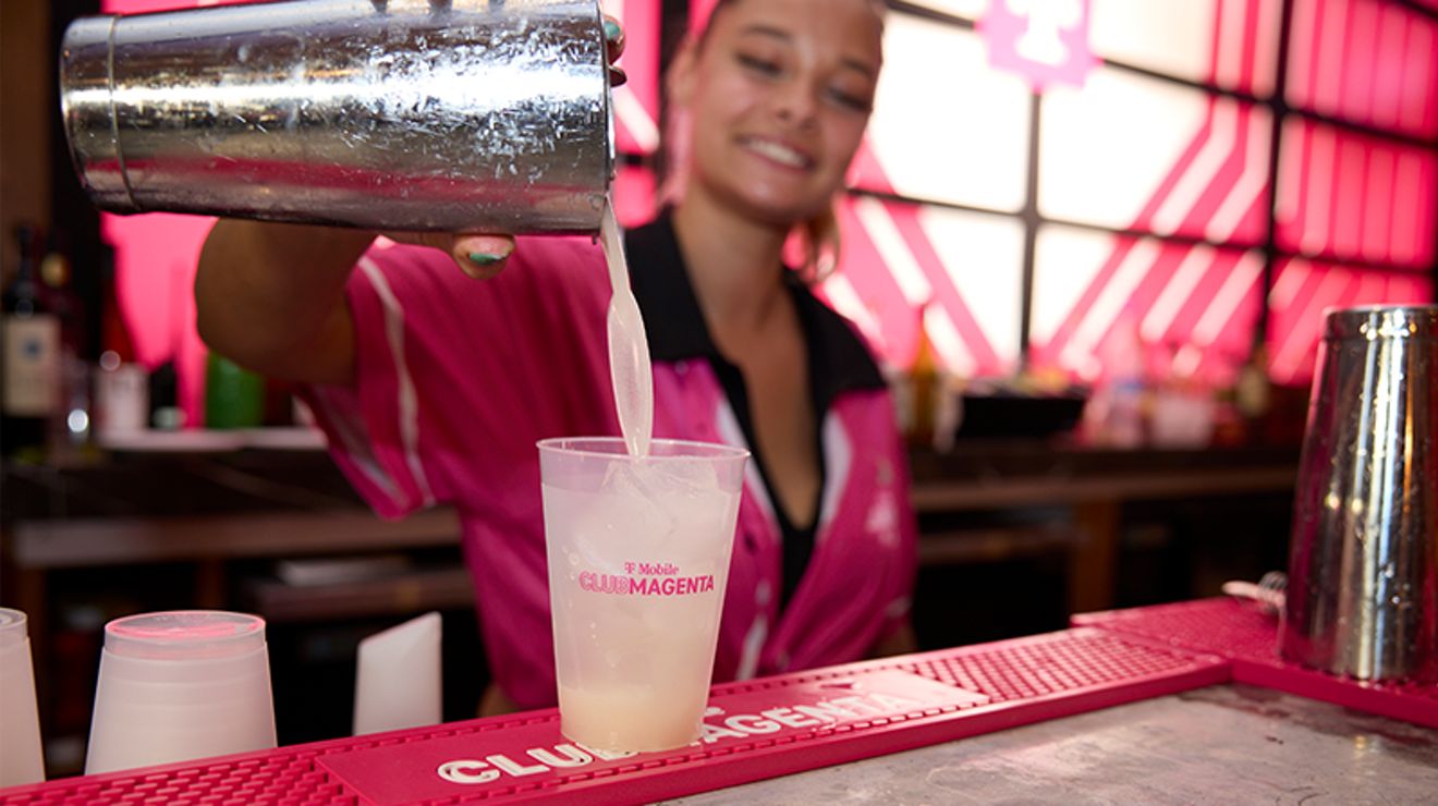 Bartender pouring a mixed drink at the Club Magenta bar.