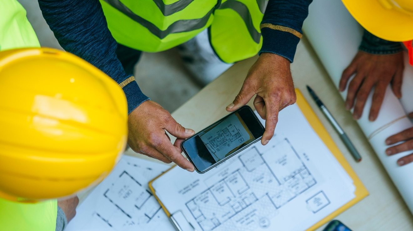 Construction workers taking photo of floor plans