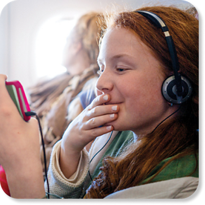 During a flight, a girl listens to headphones while staring at her phone.