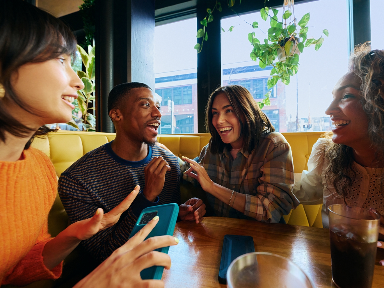 A group of friends is smiling and laughing as they converse together in a restaurant.  