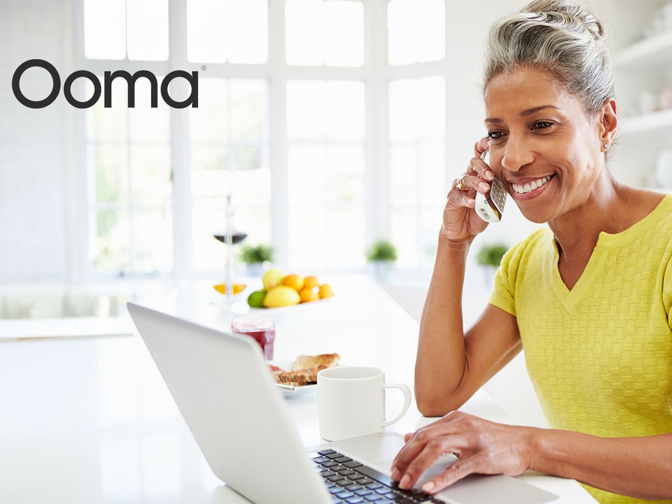 Ooma. Smiling woman talking on a landline phone.