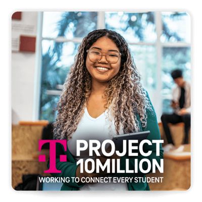 Student with laptop facing the camera and smiling.