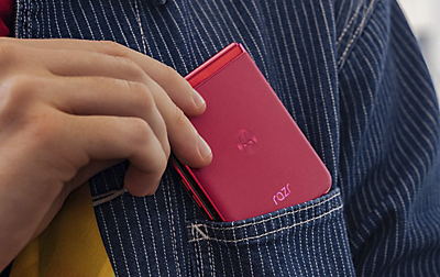 A magenta smartphone is getting pulled out a front shirt pocket.