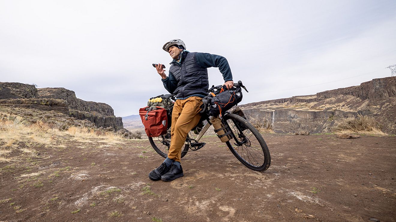 A long-distance biker talks through speakerphone on his smartphone.