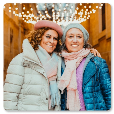 two smiling women wearing coats and hats