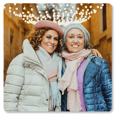 two smiling women wearing coats and hats