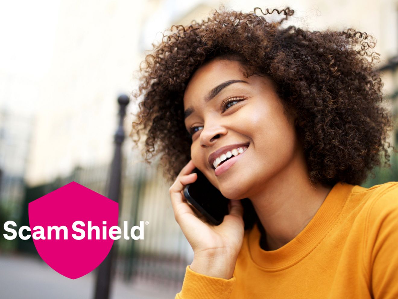 A hand holding a phone, showing the blocked calls feature on the screen, next to the ScamShield logo