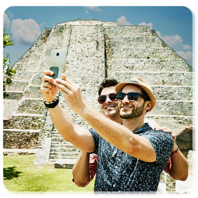 Two men smile for a selfie in front of an ancient temple.