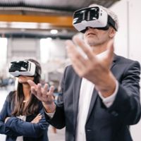 A man and a woman using VR goggles and wearing black suit jackets.