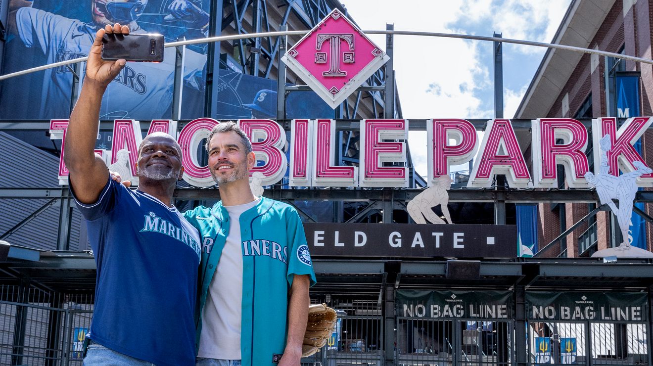 ​​Two men take a selfie while standing outside of T-Mobile Park.​ 