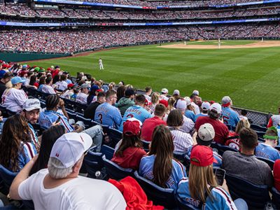 A crowd seated, watching a game at a baseball stadium.
