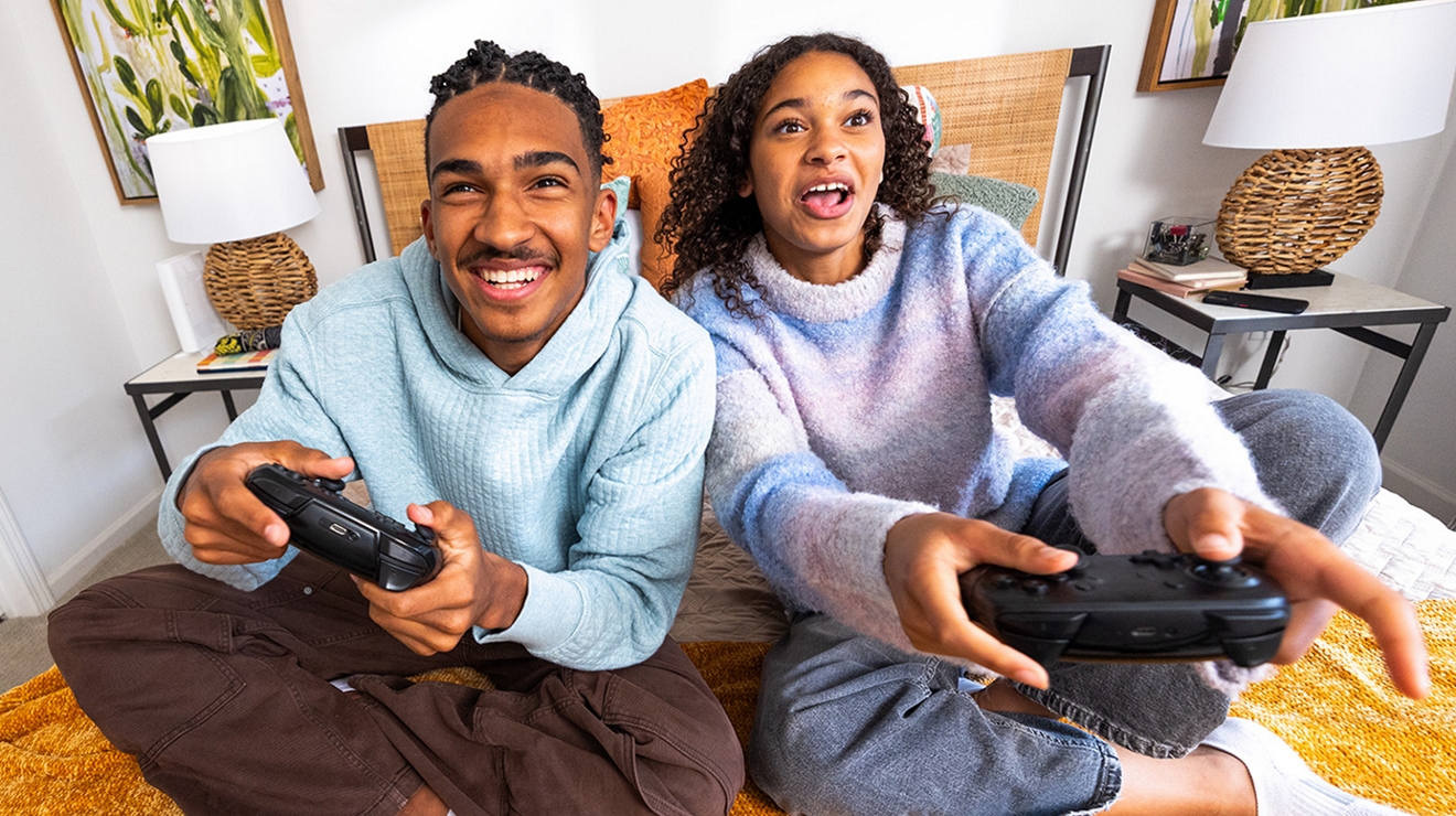 Two people sitting on a bed playing video game