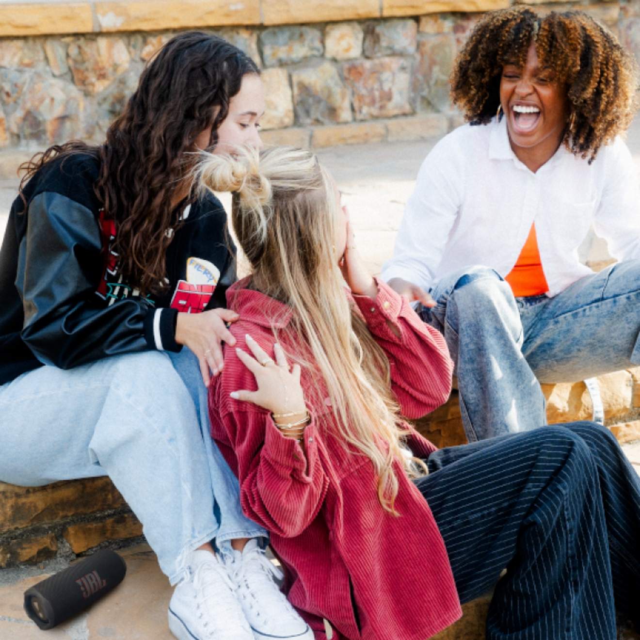 Three friends sitting listening to a JBL Flip 7 device