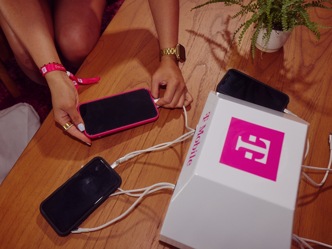 Three smartphones hooked up to a T-Mobile branded charging station. 