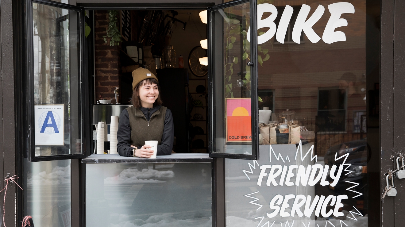 A woman drinking a cup of coffee in an open window.