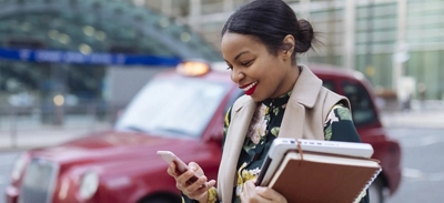 Una mujer mirando su teléfono y sonriendo.