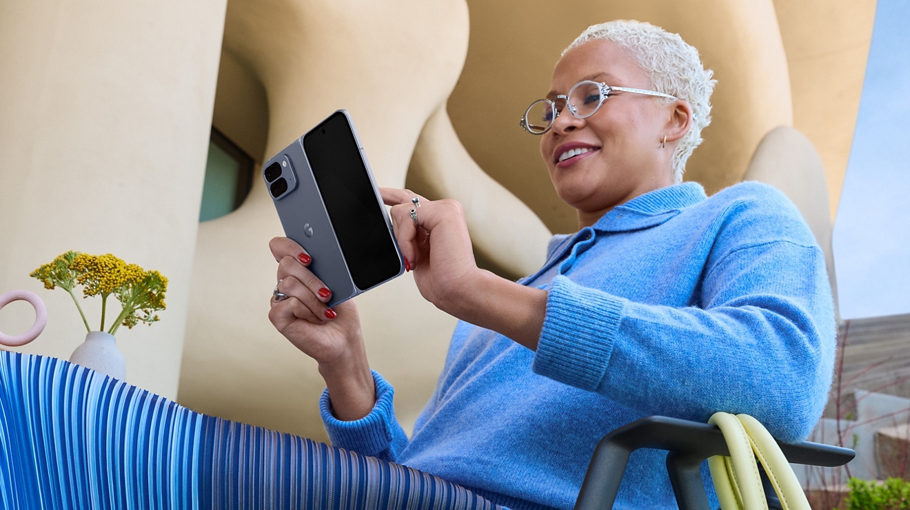 Someone relaxing outdoors, holding a Google Pixel 10a in one hand while checking the screen against a bright, open backdrop.