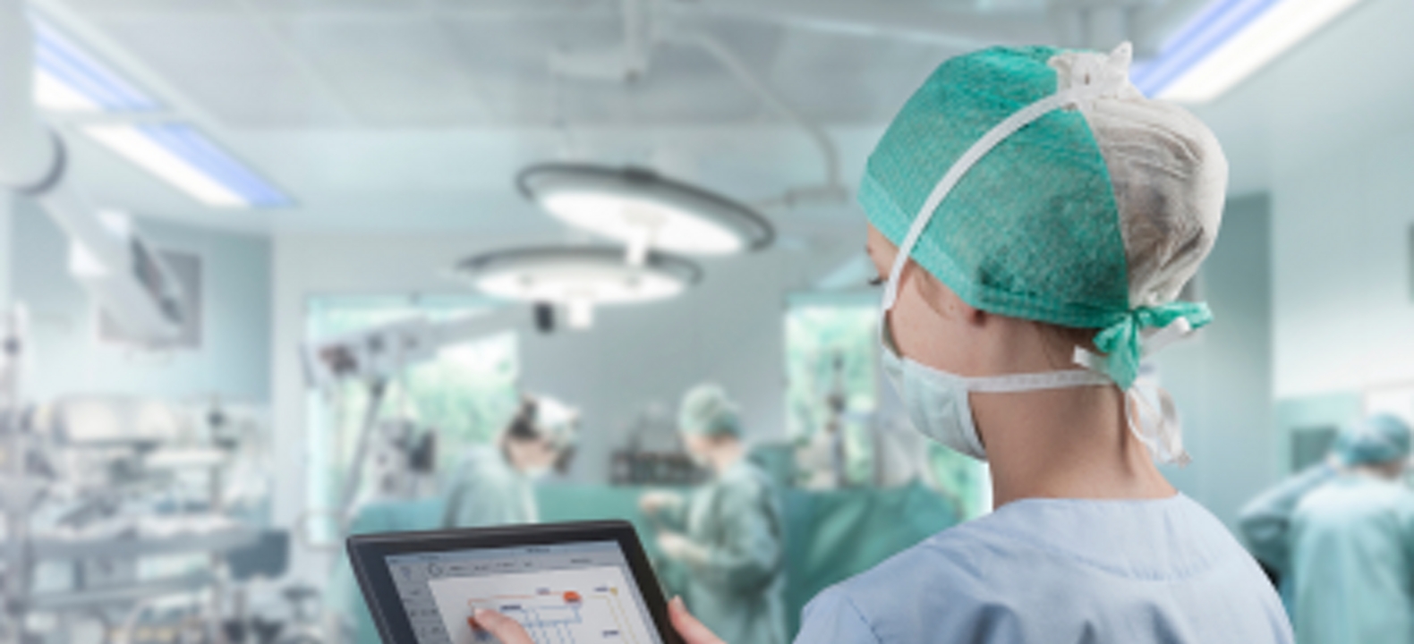 A medical professional uses a tablet in an operating room.
