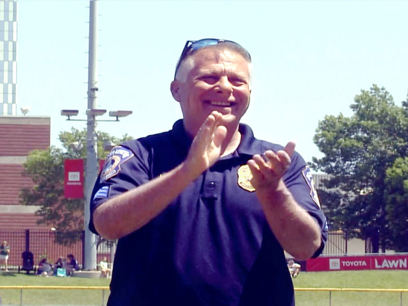 Sergeant Randy Dodd, an IMPD Reserve Officer, applauds while standing on a baseball field.