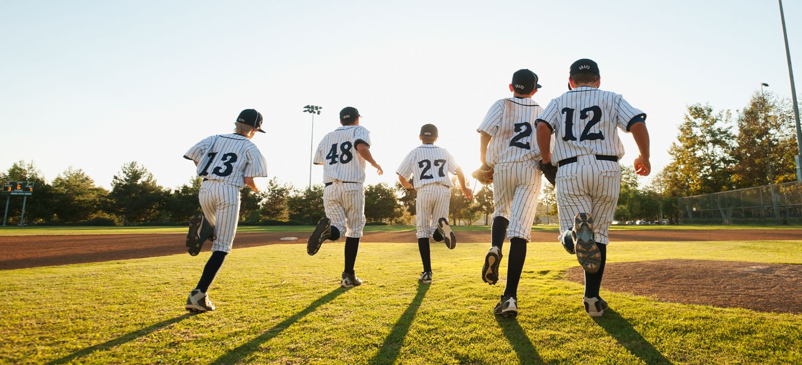 Little League players running across a baseball field. 
