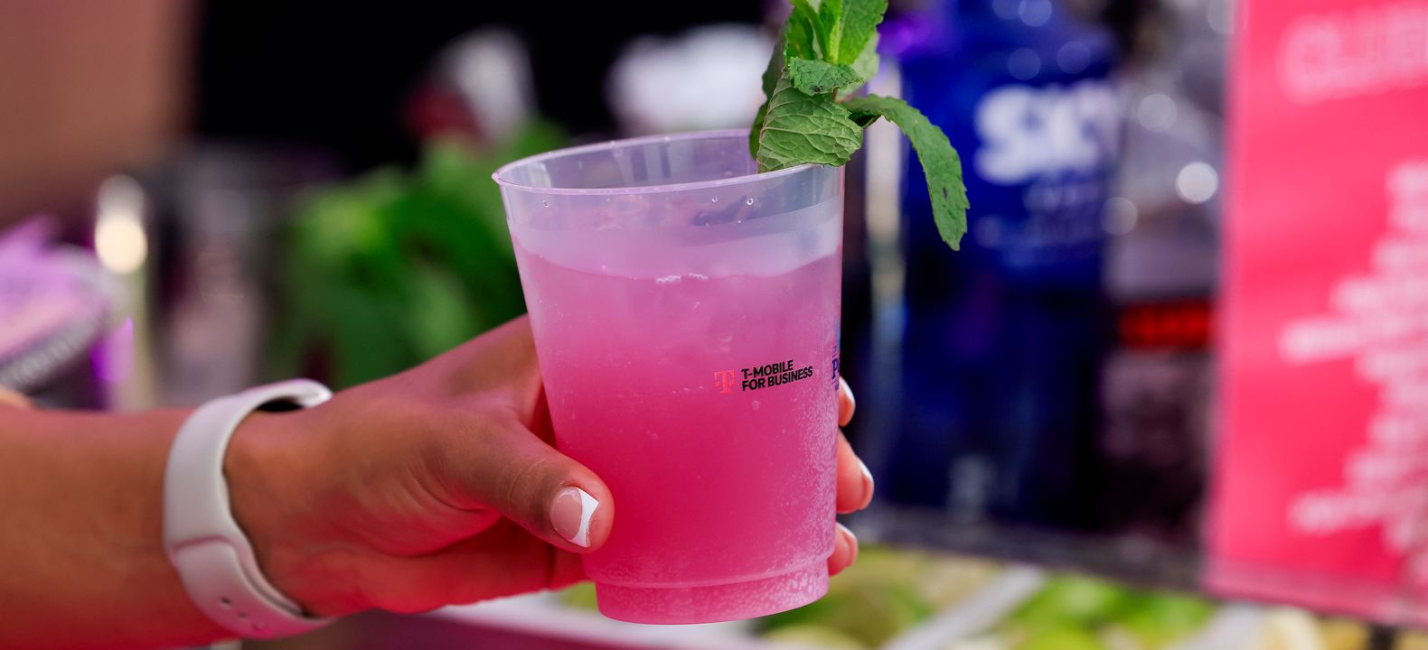 A hand holding up a Magenta cocktail. 