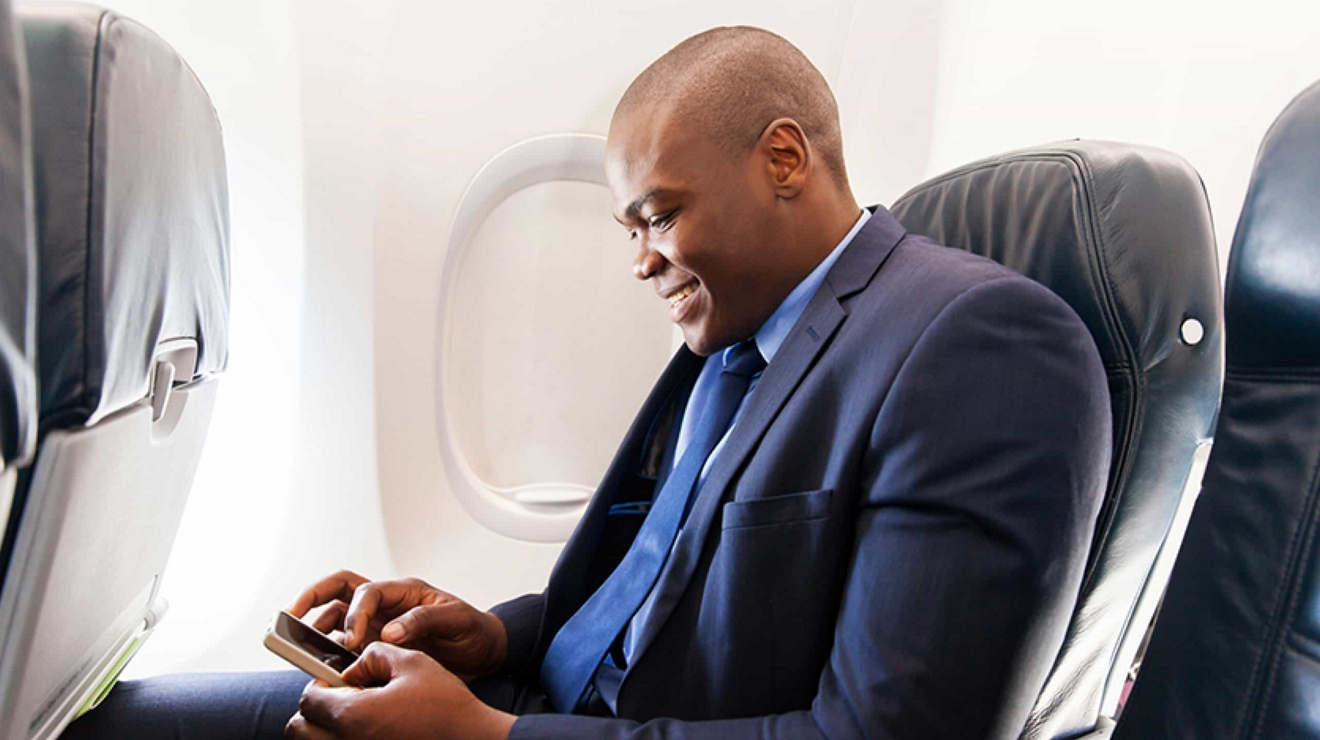 A business traveler enjoys in-flight Wi-Fi on their smartphone and stays productive in the air.