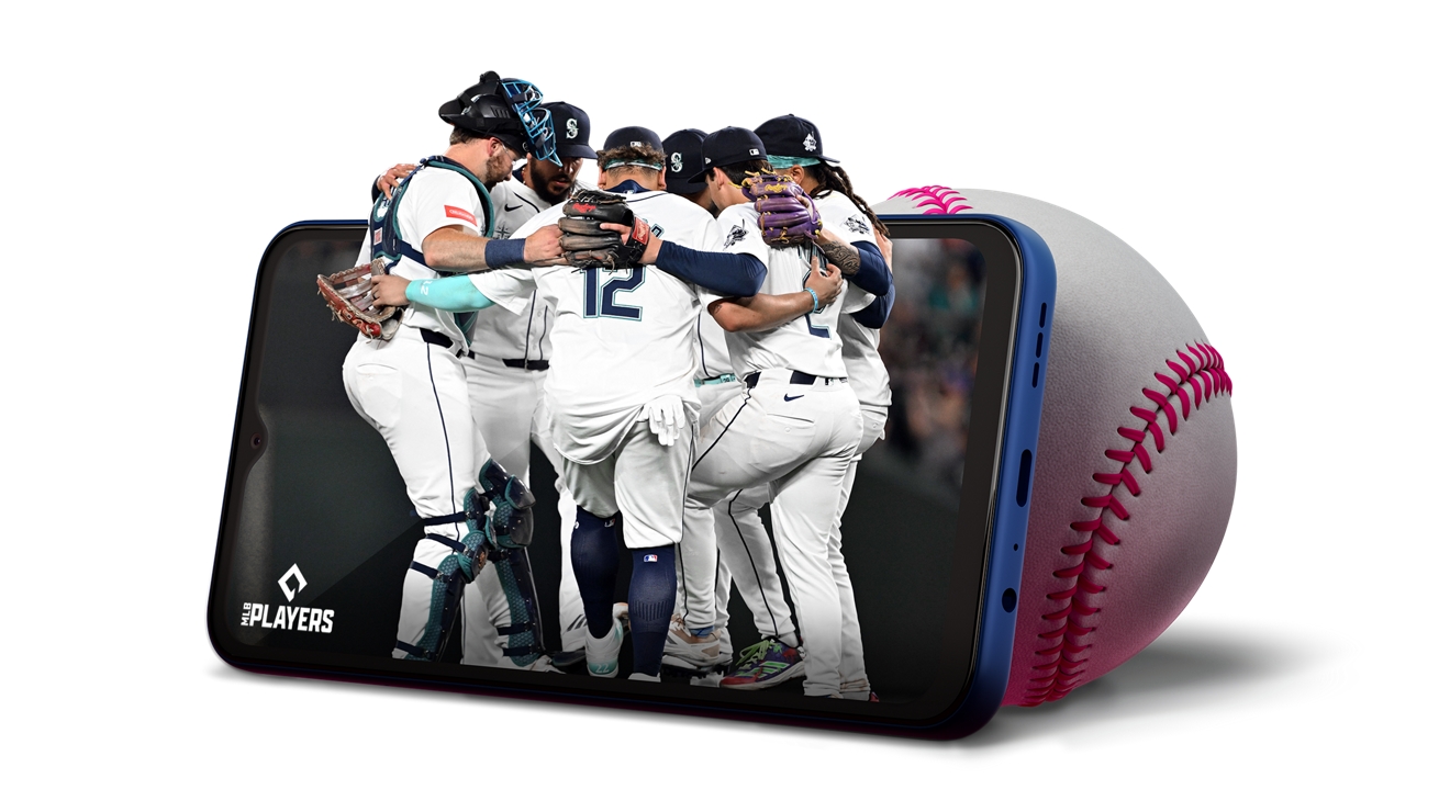 A baseball team huddles together in a moment coming out of a phone, which is propped up on a baseball.
