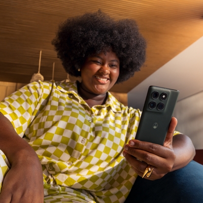 A young lady checks on her moto edge while smiling.