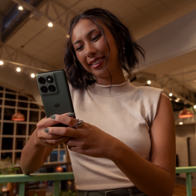 A young lady checks on her moto edge while smiling.