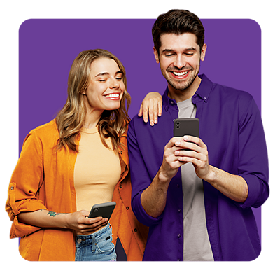 A man and woman smiling while looking at phone.