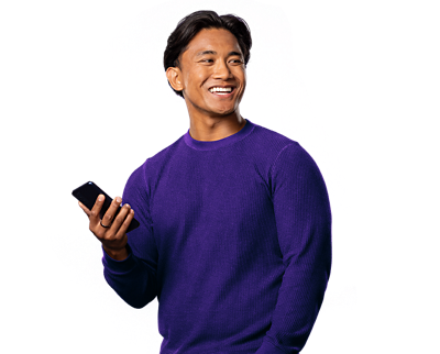 Young male adult in a purple long-sleeve shirt, looking around while holding a phone in his right hand.