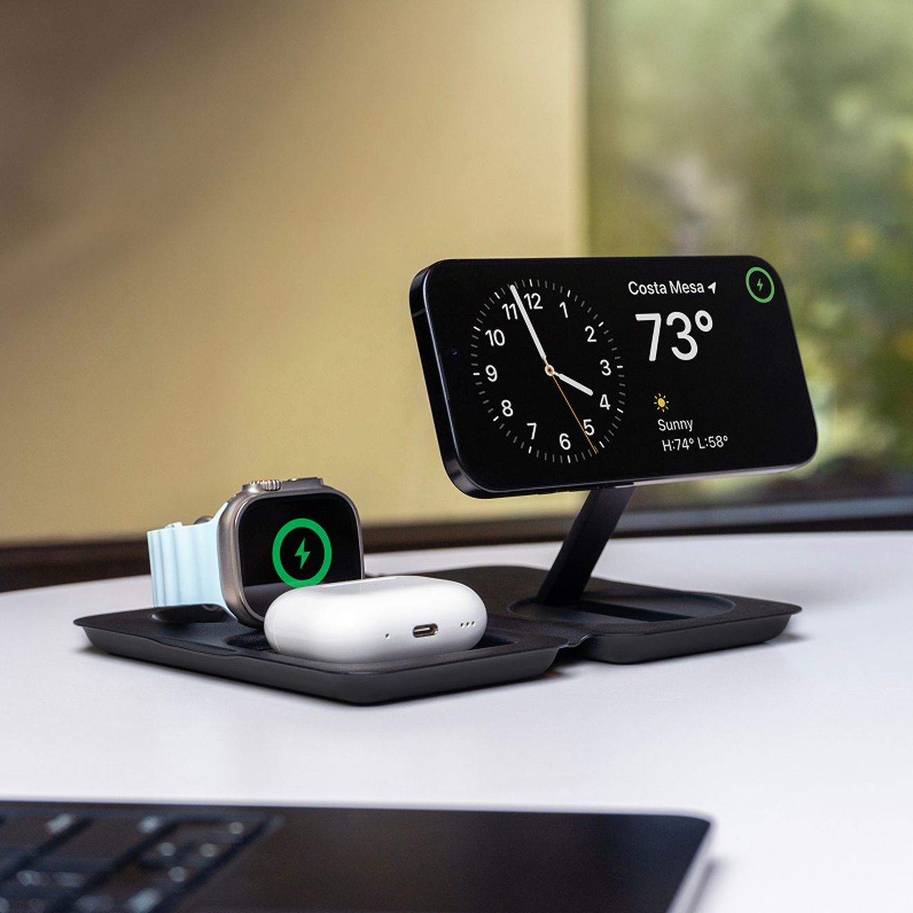 A 3-in-1 wireless charging dock simultaneously charges an iPhone, Apple Watch, and AirPods on a desk.
