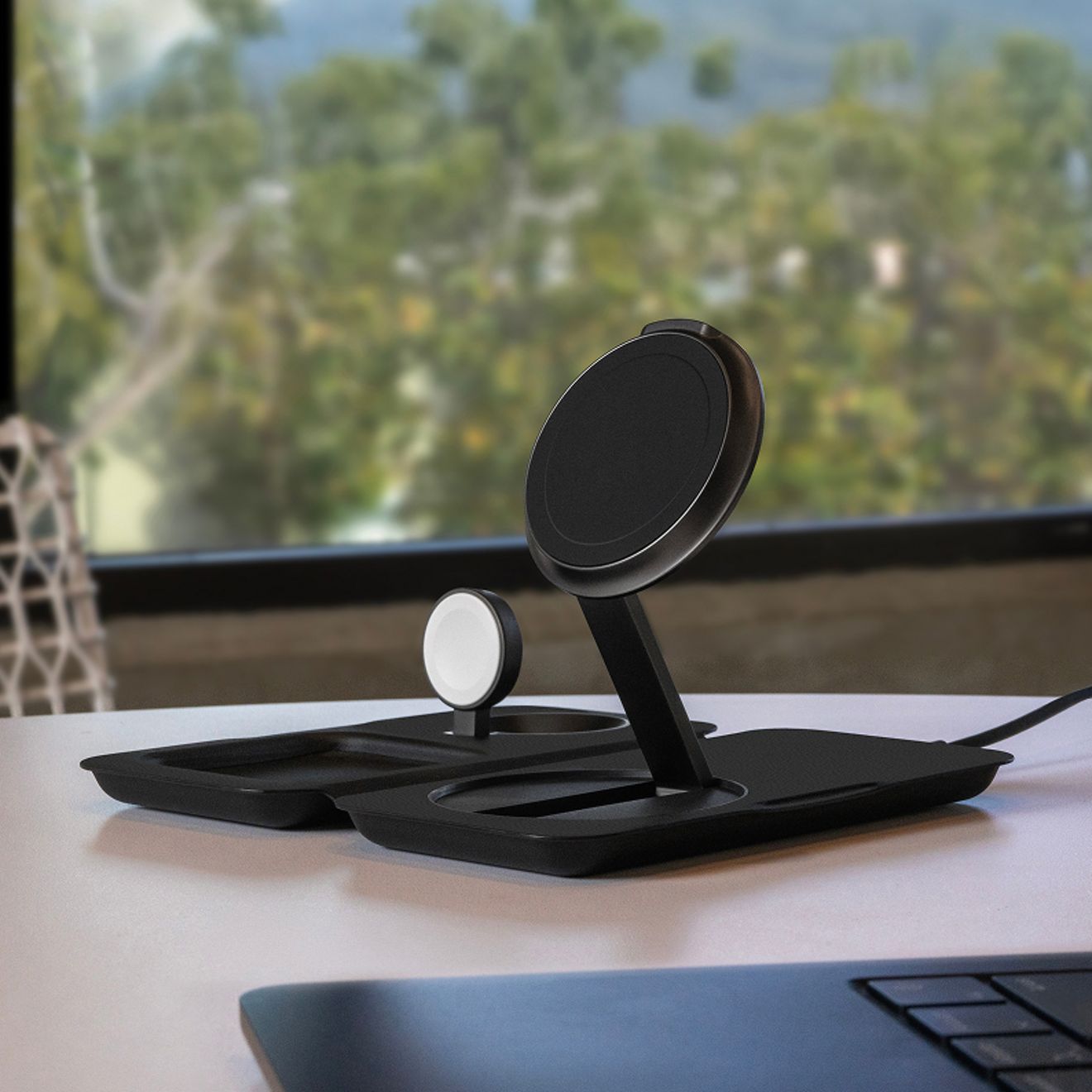 A black Nimble Fold 3-in-1 wireless charging station sits unfolded on a desk, with dedicated charging areas for a smartphone, Apple Watch, and wireless earbuds.