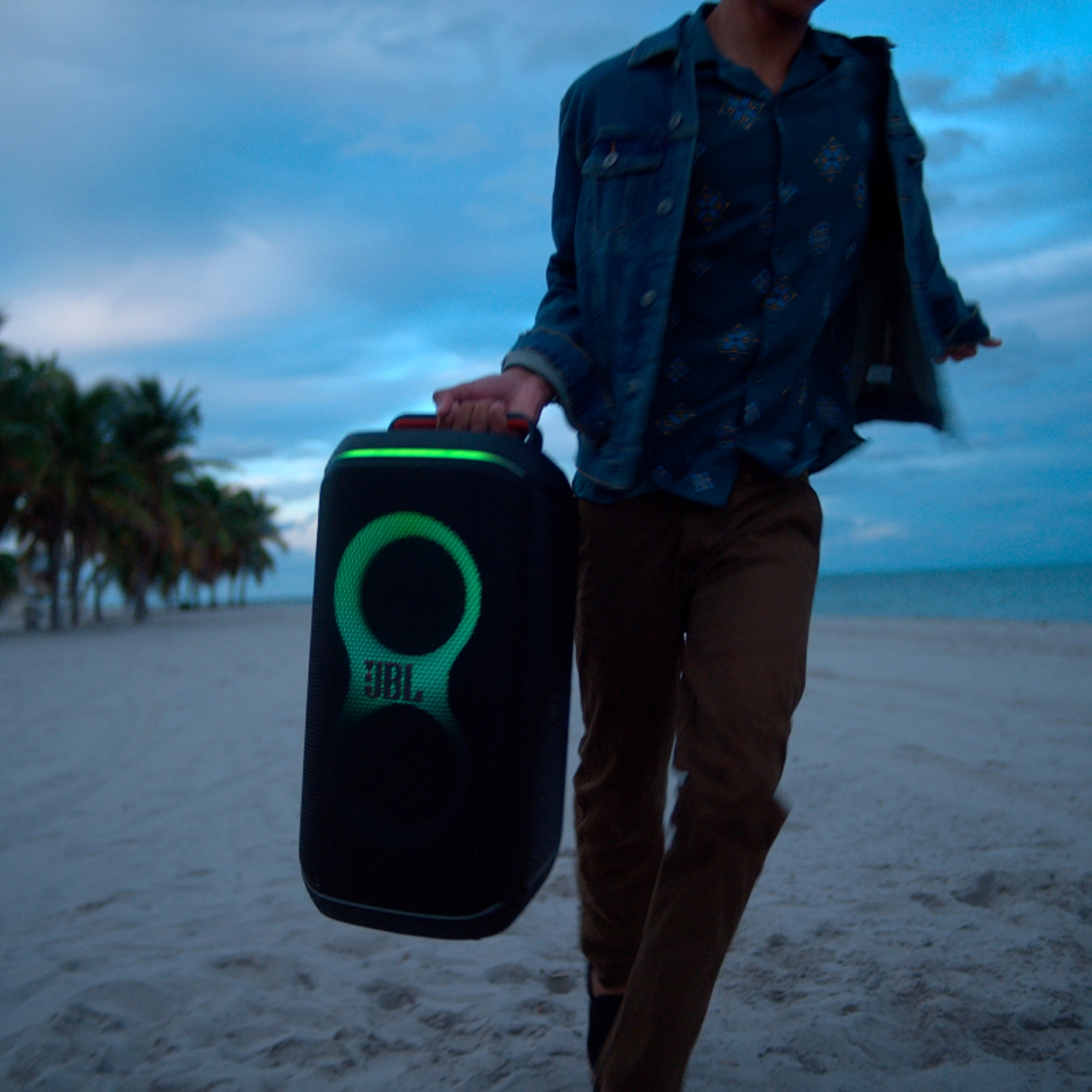 A person carrying a JBL PartyBox Club 120 by its foldable handle