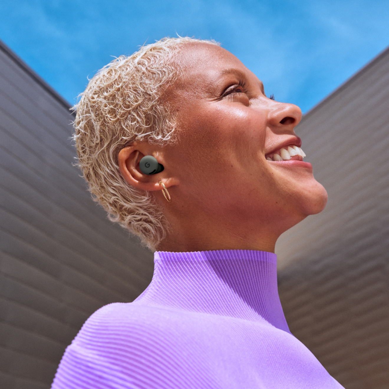 A woman smiling while using Google Pixel Buds 2a