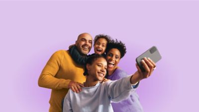 Familia de cuatro personas tomándose una selfie grupal con un smartphone