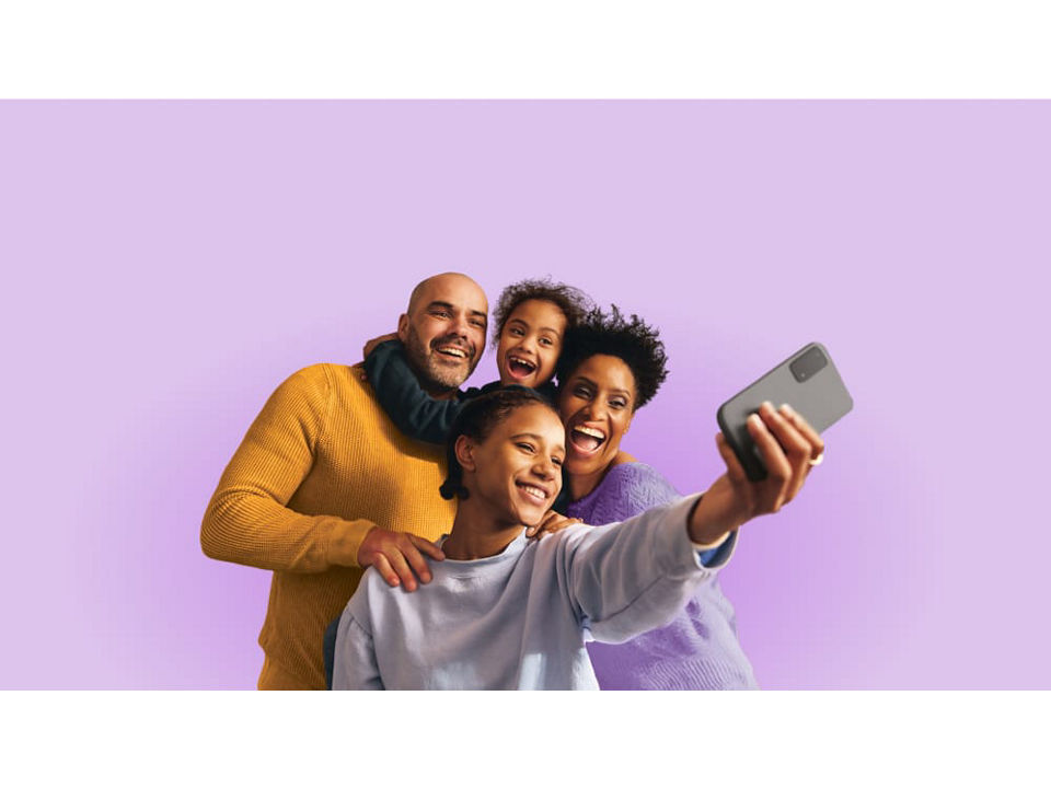 Familia de cuatro personas tomándose una selfie grupal con un smartphone