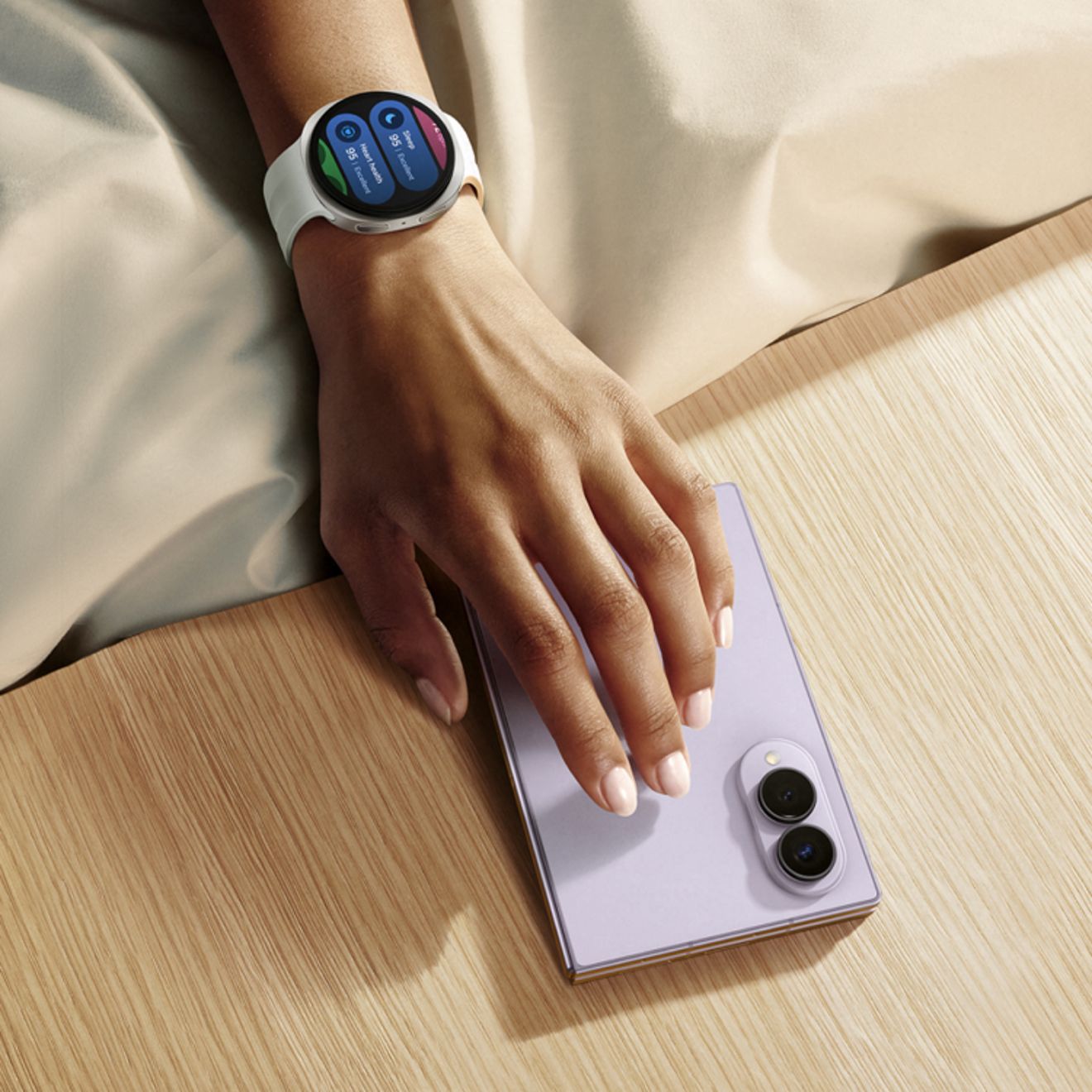 Samsung Galaxy Z Fold8 in light purple, shown closed on a tabletop next to a Galaxy Watch with a white band.