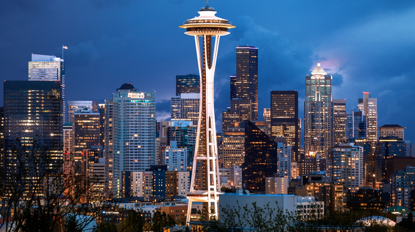 The Seattle skyline at dusk, with the Space Needle standing bright against the dark sky.
