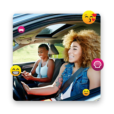 Two girls driving while laughing, surrounded by emojis.