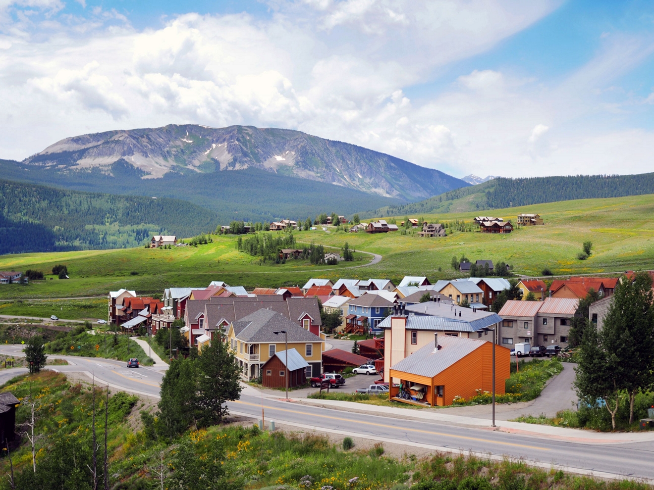 A small cluster of homes stands beside a rural road in a mountain community.