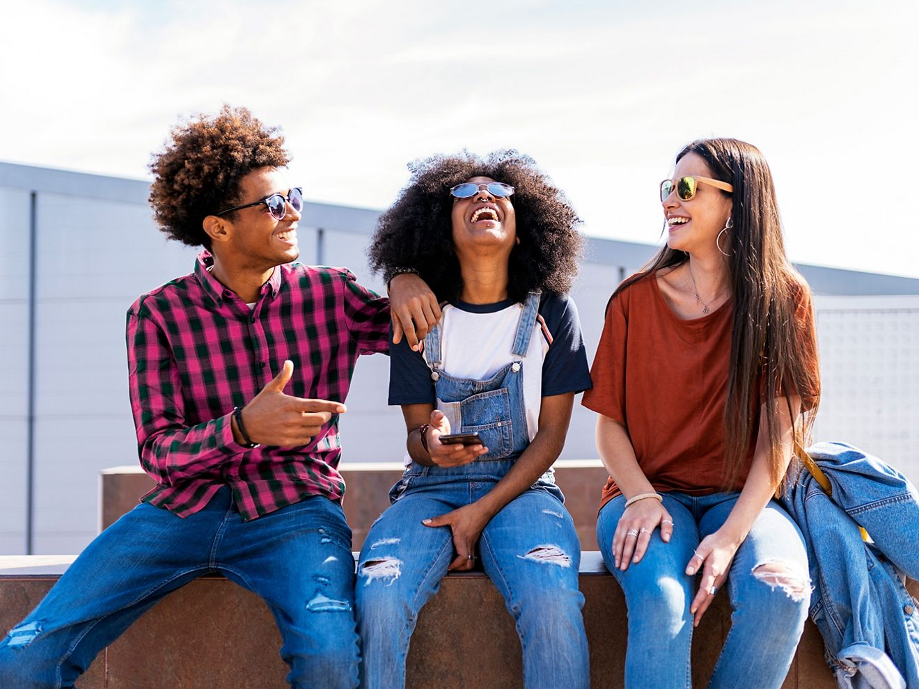 Three friends laugh about something on their phone.