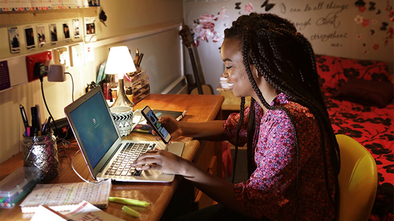 A woman working on her laptop in a college room.
