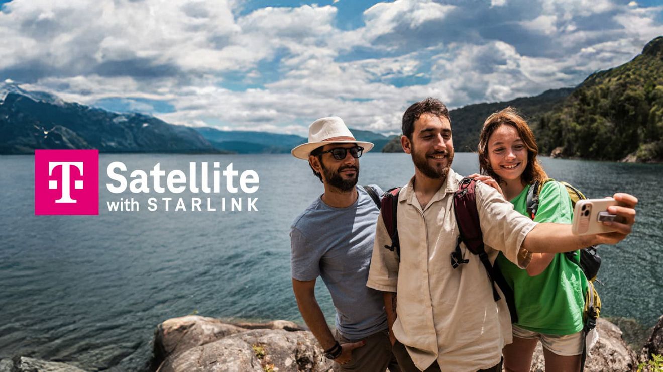 Group of friends taking a selfie on a rocky lakeshore with mountains in the background and “T Satellite with Starlink” text.