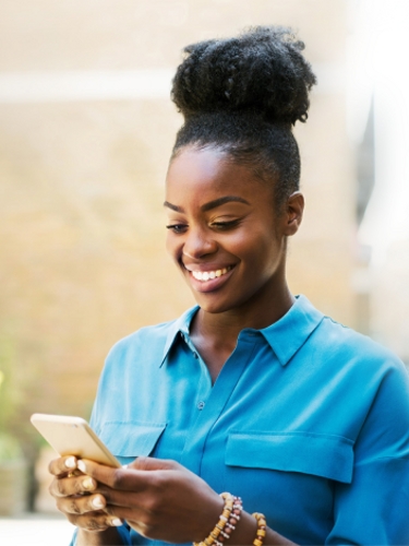 A smiling financial services professional uses her smartphone while standing outside
