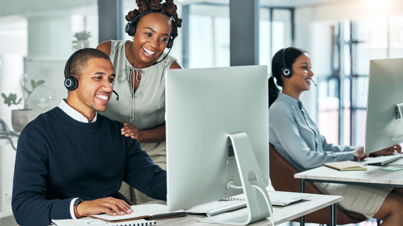 Three smiling sales professionals speak with customers by phone.