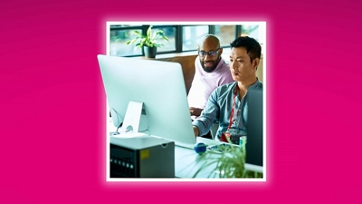 A business professional and their colleague work together at a computer. 