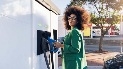 A customer at a gas station holds an electric vehicle charger.