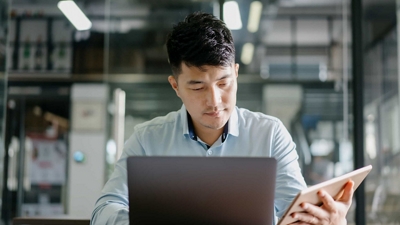 A business professional works on a laptop and a tablet, safeguarded by automatic data-security.